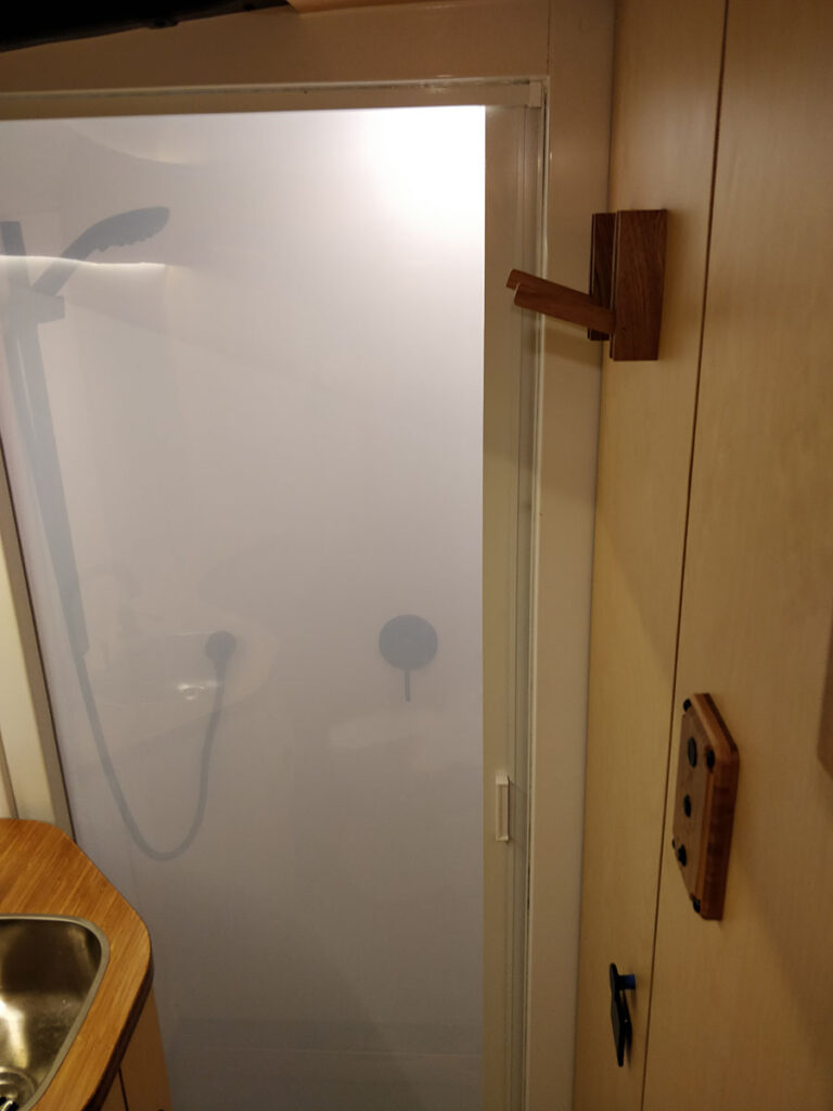 Looking into the Shower from the toilet with the opaque retractable shower door closed.